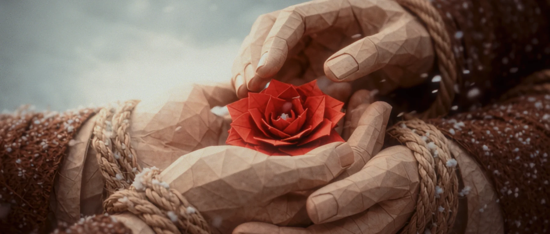 A red paper flower resting in bound hands